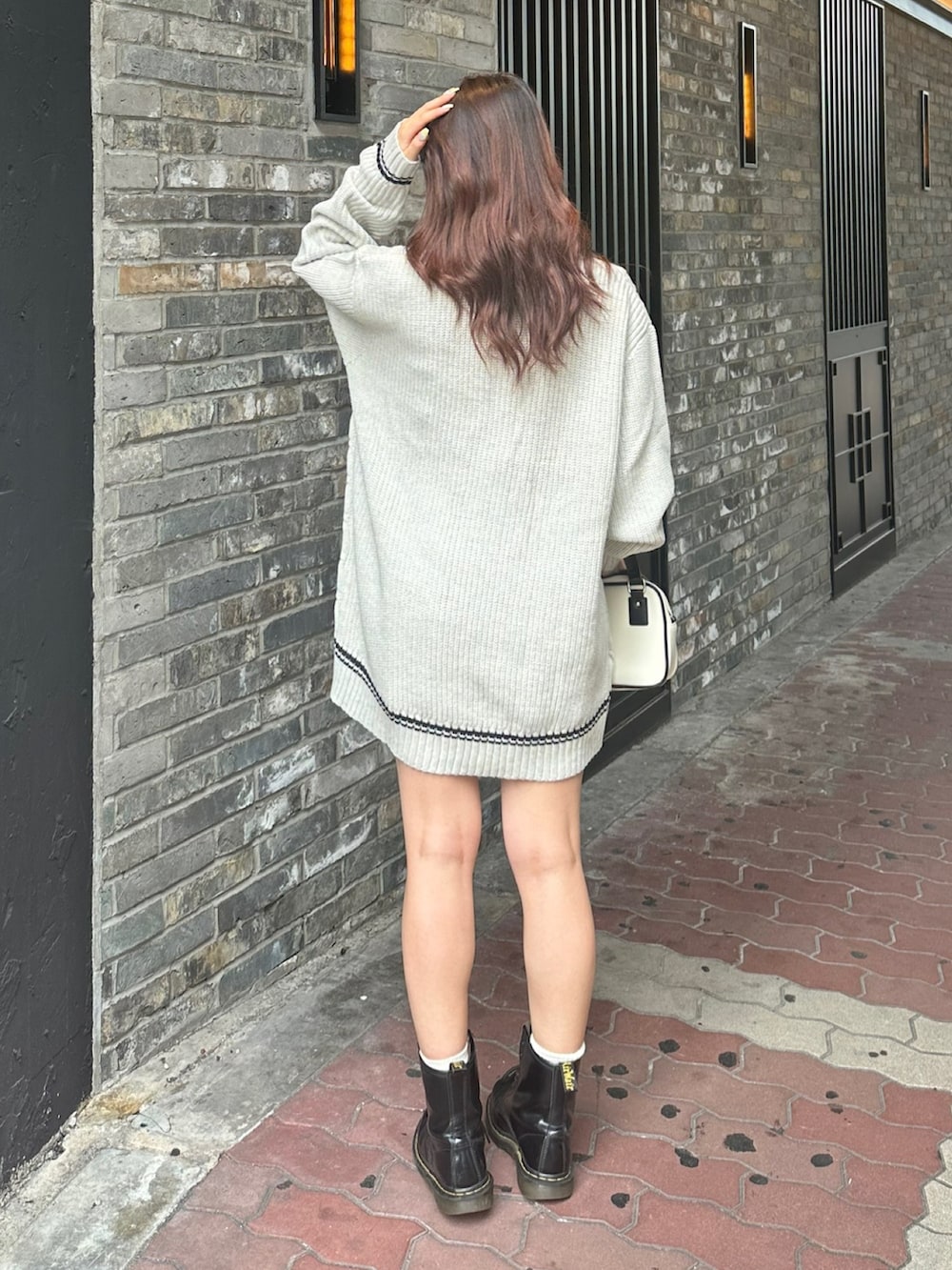 グレー系のニット/セーター、ホワイト系のショルダーバッグを着用したレディースの夏コーディネートの3枚目の写真