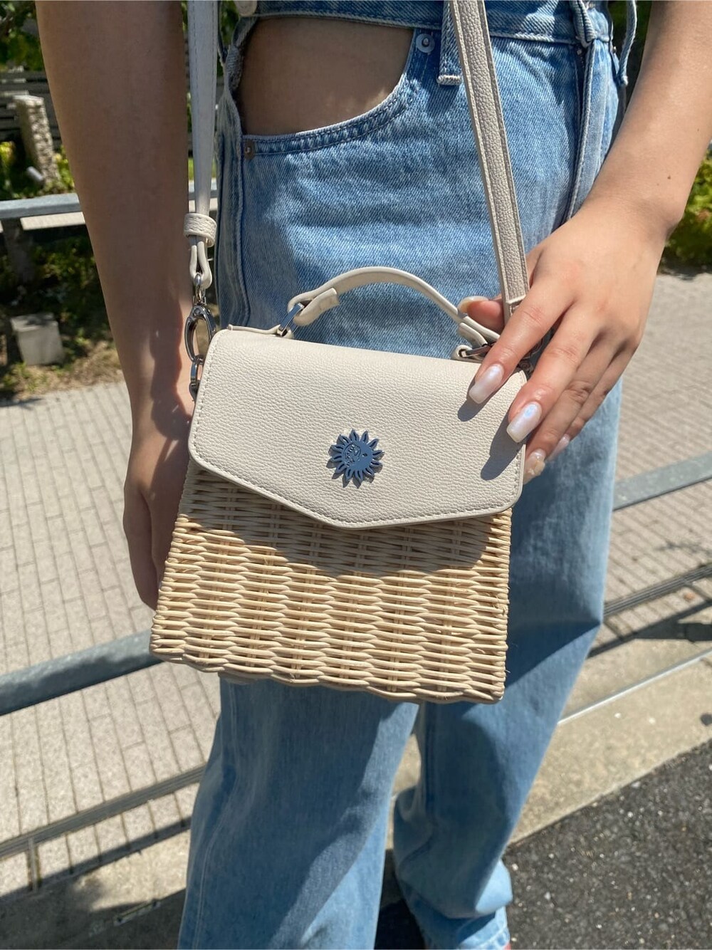 ブルー系のデニムパンツ、ブラック系のサンダル、ホワイト系のショルダーバッグを着用したレディースの夏コーディネートの8枚目の写真