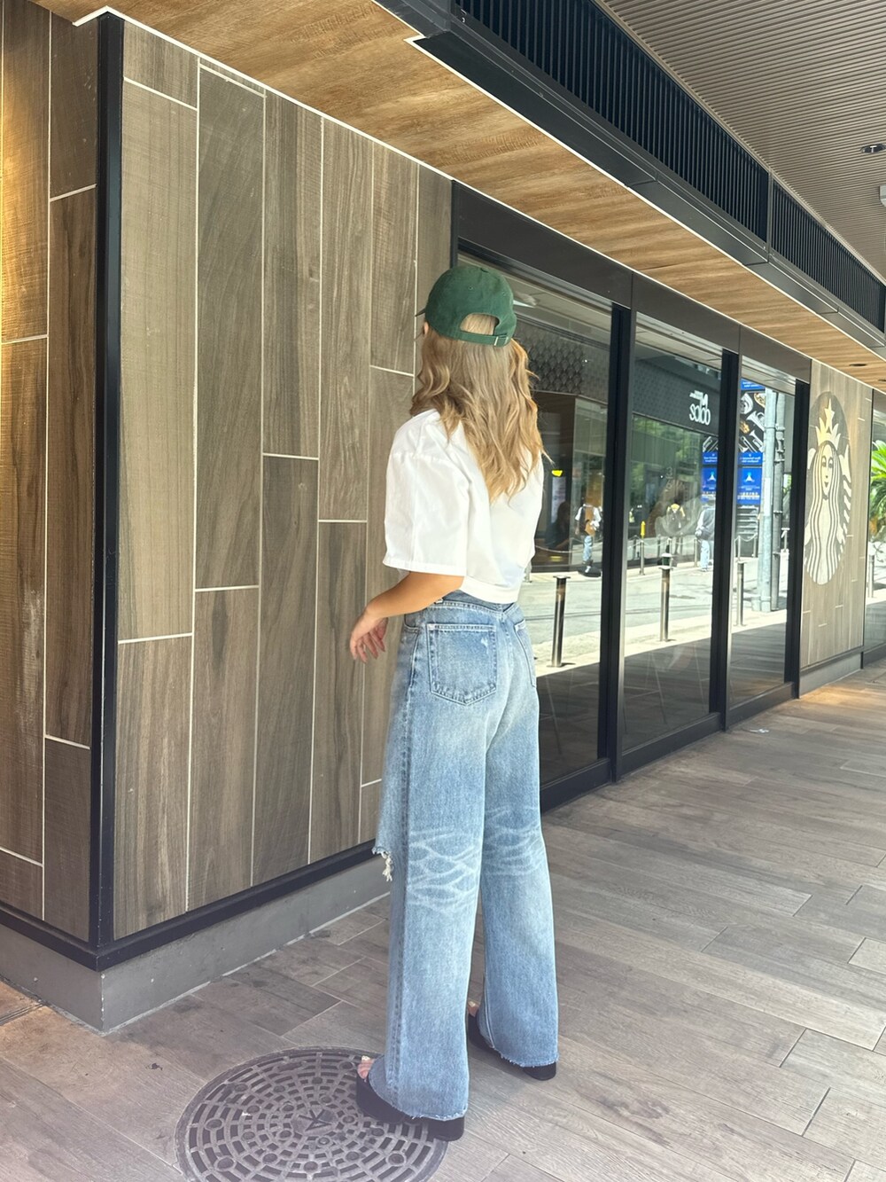 ホワイト系のシャツ/ブラウス、ブラック系のデニムパンツ、ブラック系のサンダルを着用したレディースの夏コーディネートの2枚目の写真