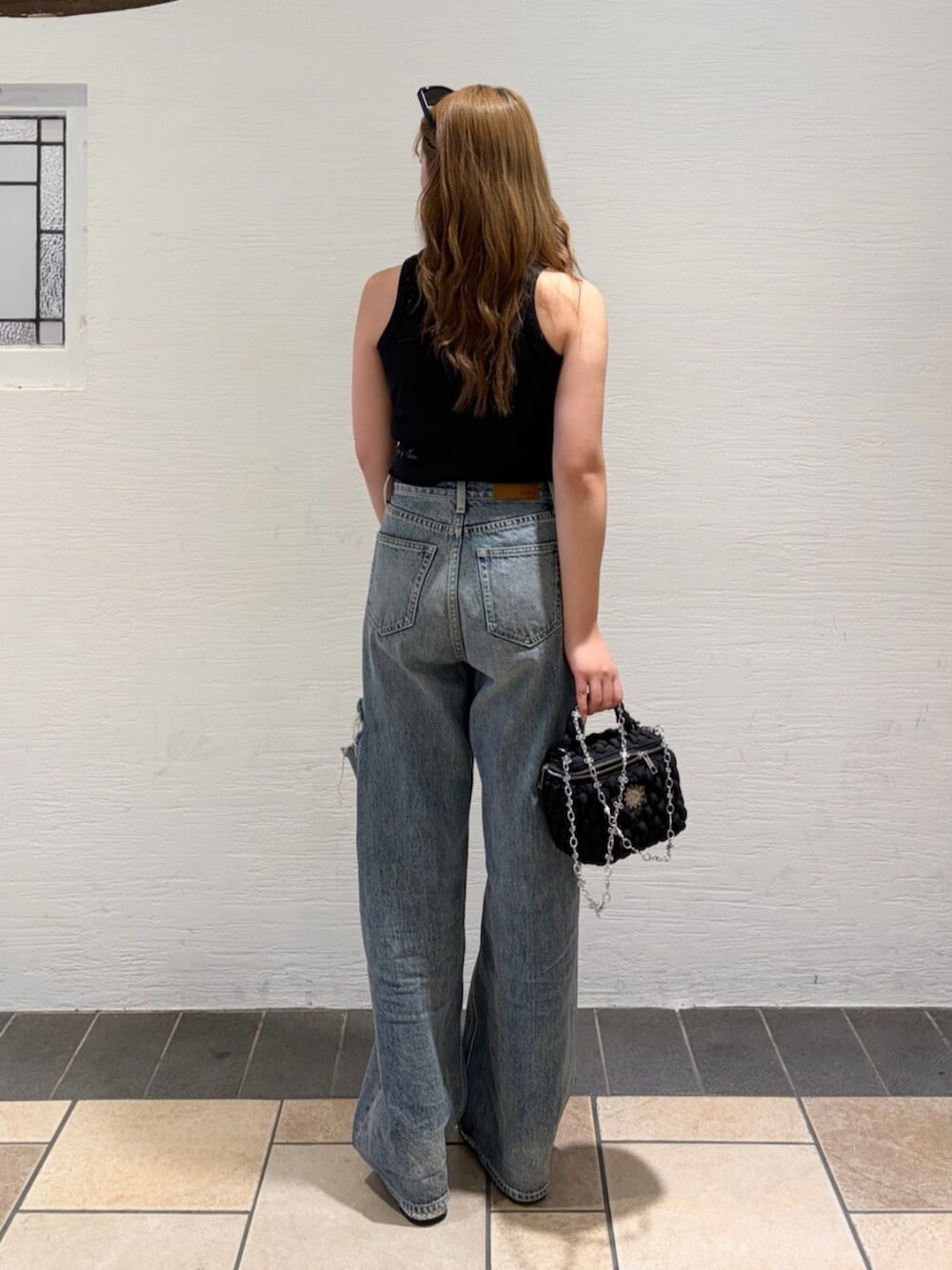 ブルー系のデニムパンツ、ブラック系のショルダーバッグ、シルバー系のサンダルを着用したレディースの夏コーディネートの3枚目の写真
