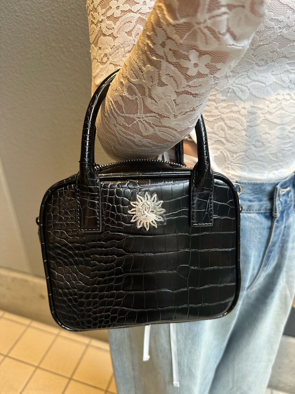 ブルー系のデニムパンツ、ホワイト系のTシャツ/カットソー、ブラック系のショルダーバッグを着用したレディースの春コーディネートの7枚目の写真