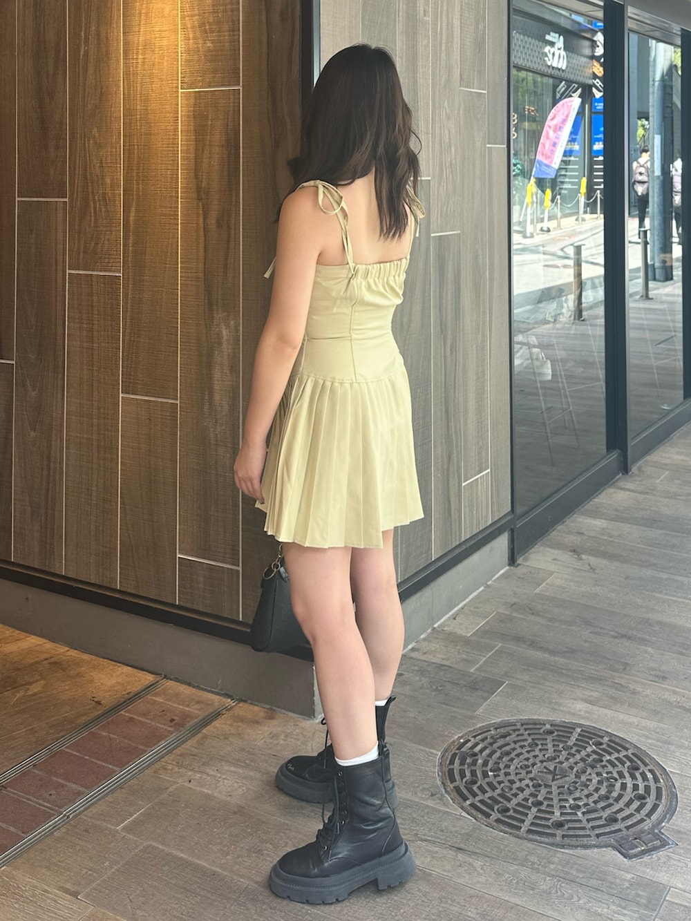 イエロー系のワンピース、ブラック系のブーツ、ブラック系のハンドバッグを着用したレディースの夏コーディネートの2枚目の写真