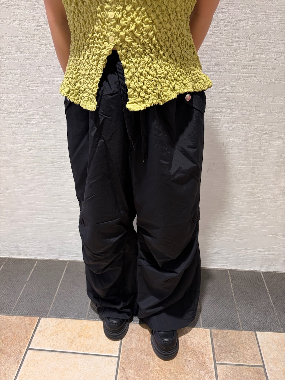 ブラック系のカーゴパンツ、イエロー系のキャミソール、ブルー系のキャップを着用したレディースの春コーディネートの7枚目の写真