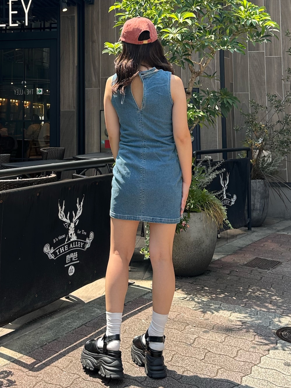 ブルー系のワンピース、ブラック系のサンダル、レッド系のキャップを着用したレディースの夏コーディネートの4枚目の写真