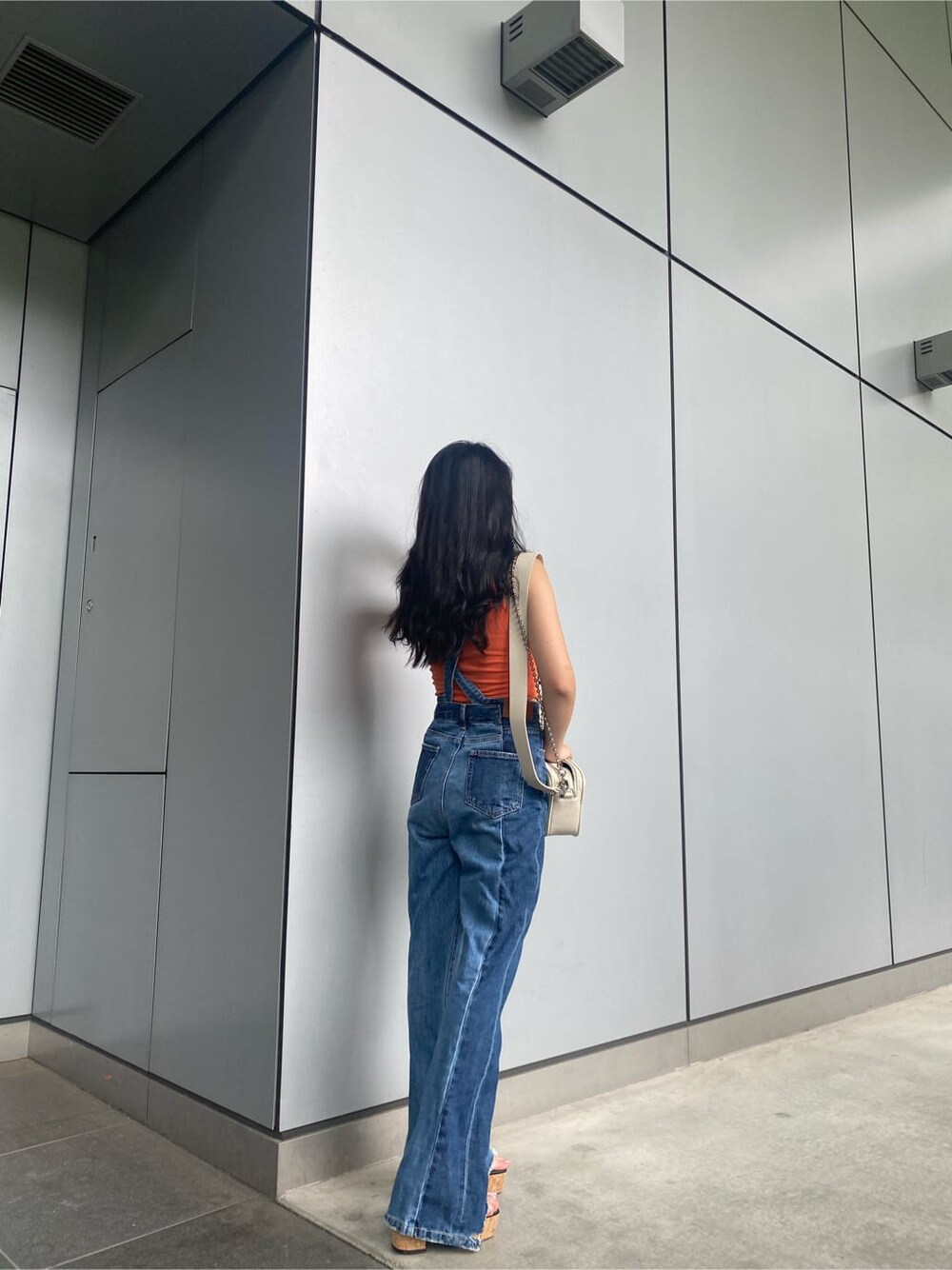 ホワイト系のショルダーバッグ、ブルー系のサロペット/オーバーオール、オレンジ系のタンクトップを着用したレディースの夏コーディネートの2枚目の写真