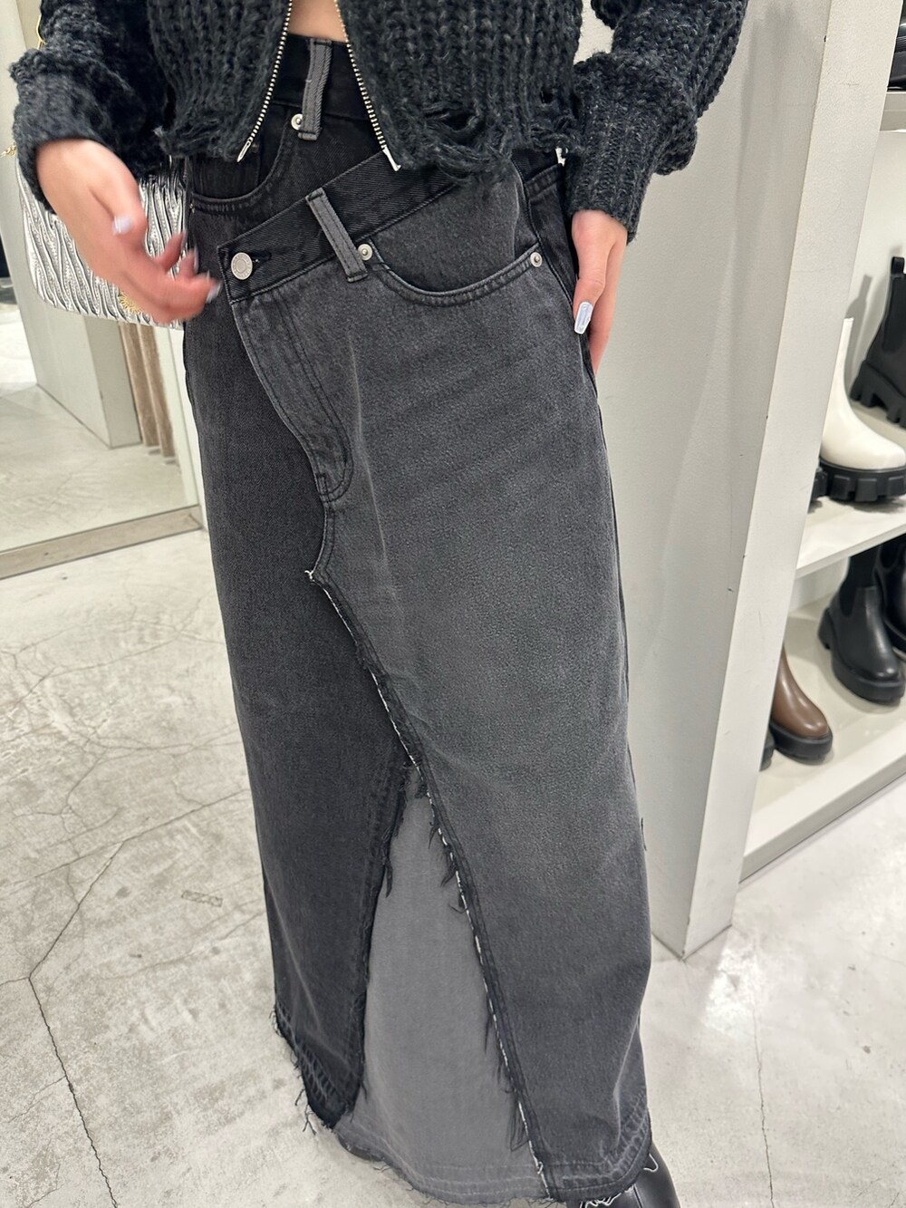 ブラック系のデニムスカート、ブラック系のニット/セーター、ブラック系のブーツを着用したレディースの冬コーディネートの7枚目の写真