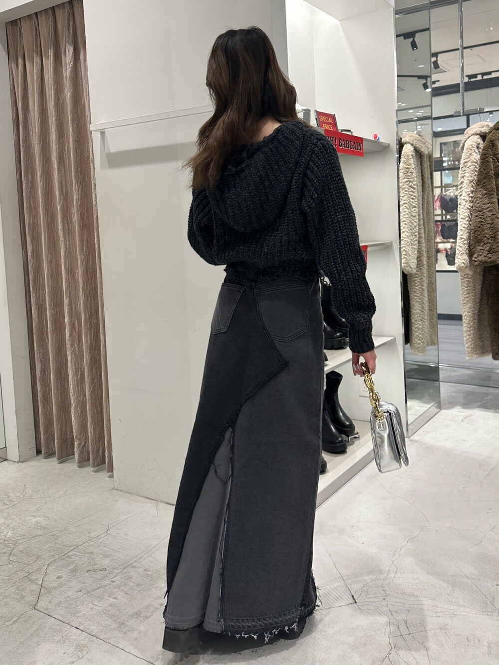 ブラック系のデニムスカート、ブラック系のニット/セーター、ブラック系のブーツを着用したレディースの冬コーディネートの3枚目の写真