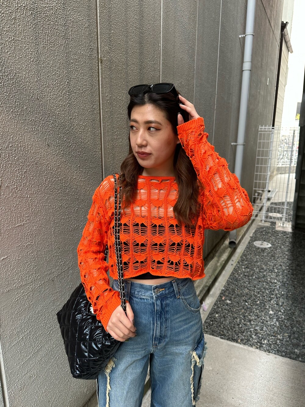 ブラック系のショルダーバッグ、ブラック系のサンダル、ブルー系のデニムパンツを着用したレディースの春コーディネートの4枚目の写真