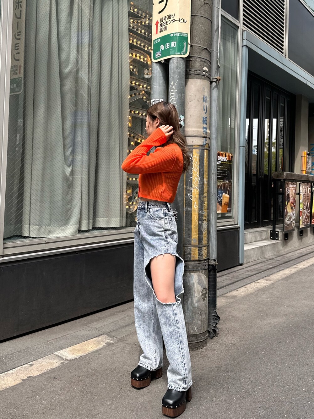 ブルー系のデニムパンツ、ブラック系のサンダル、オレンジ系のカーディガン/ボレロを着用したレディースの春コーディネートの2枚目の写真
