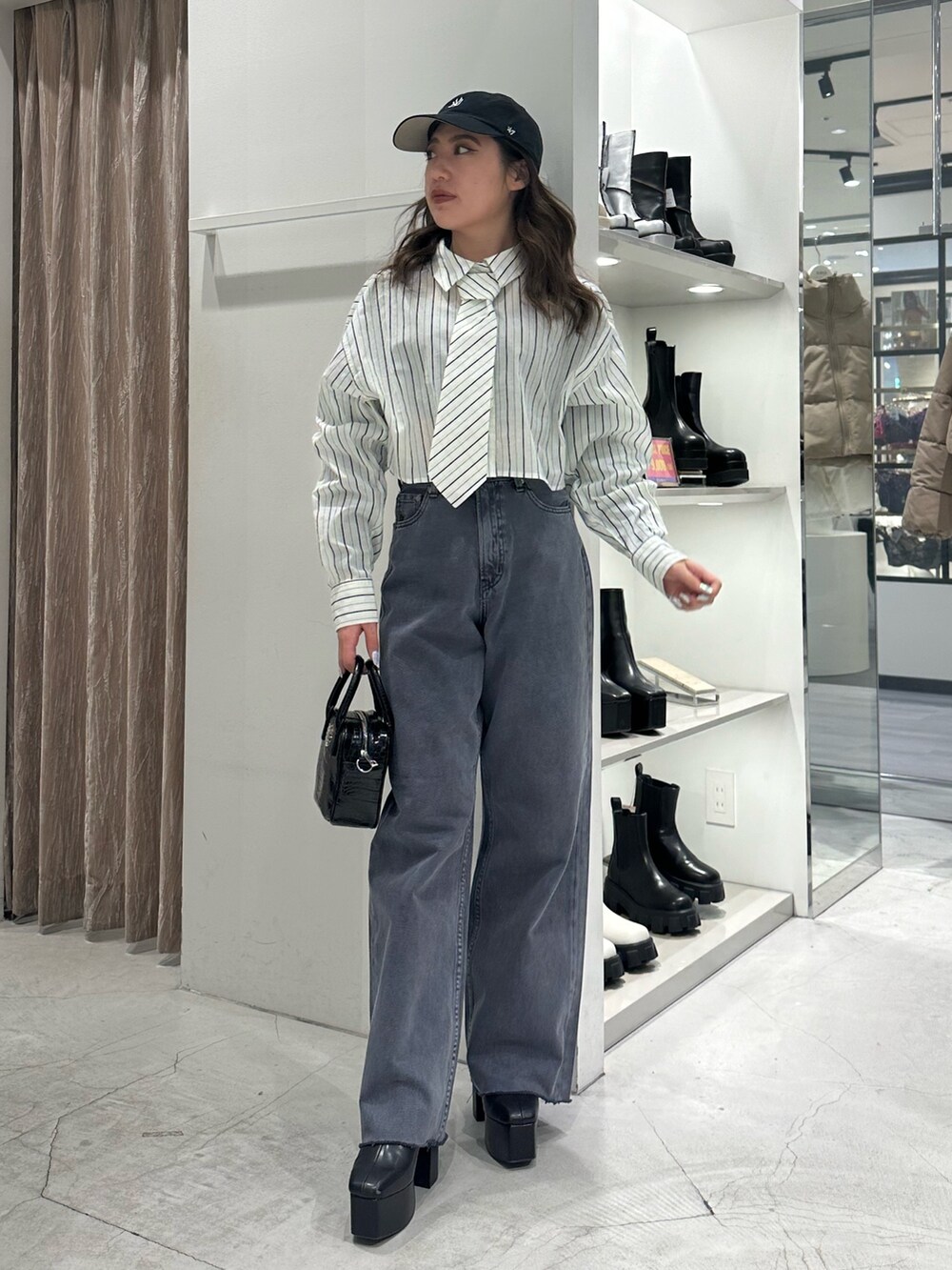 グレー系のデニムパンツ、ホワイト系のシャツ/ブラウス、ブラック系のショルダーバッグを着用したレディースの冬コーディネートの2枚目の写真