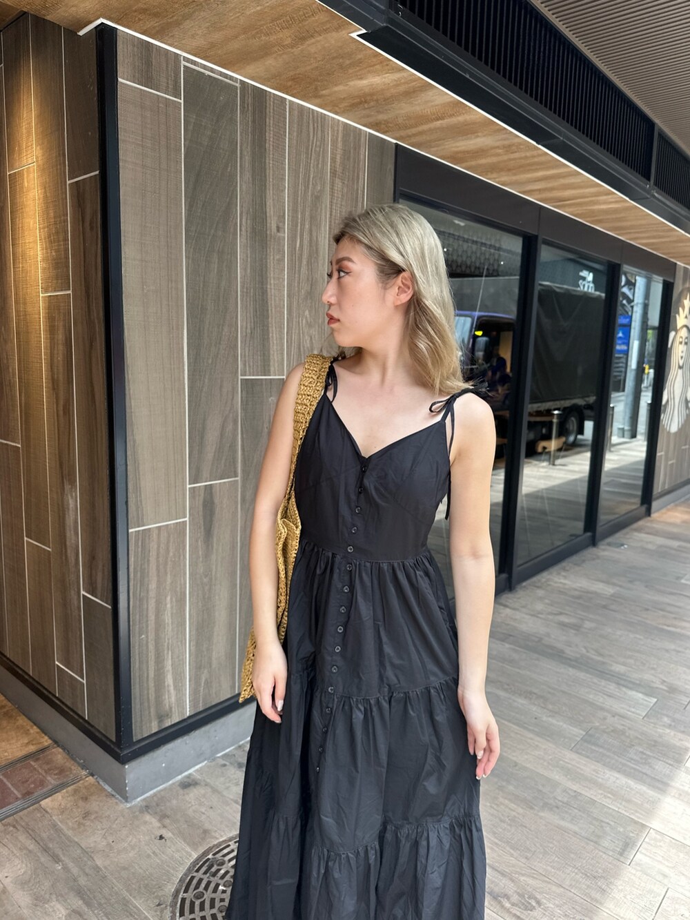 ブラック系のワンピース、ブラック系のサンダル、ベージュ系のトートバッグを着用したレディースの夏コーディネートの4枚目の写真