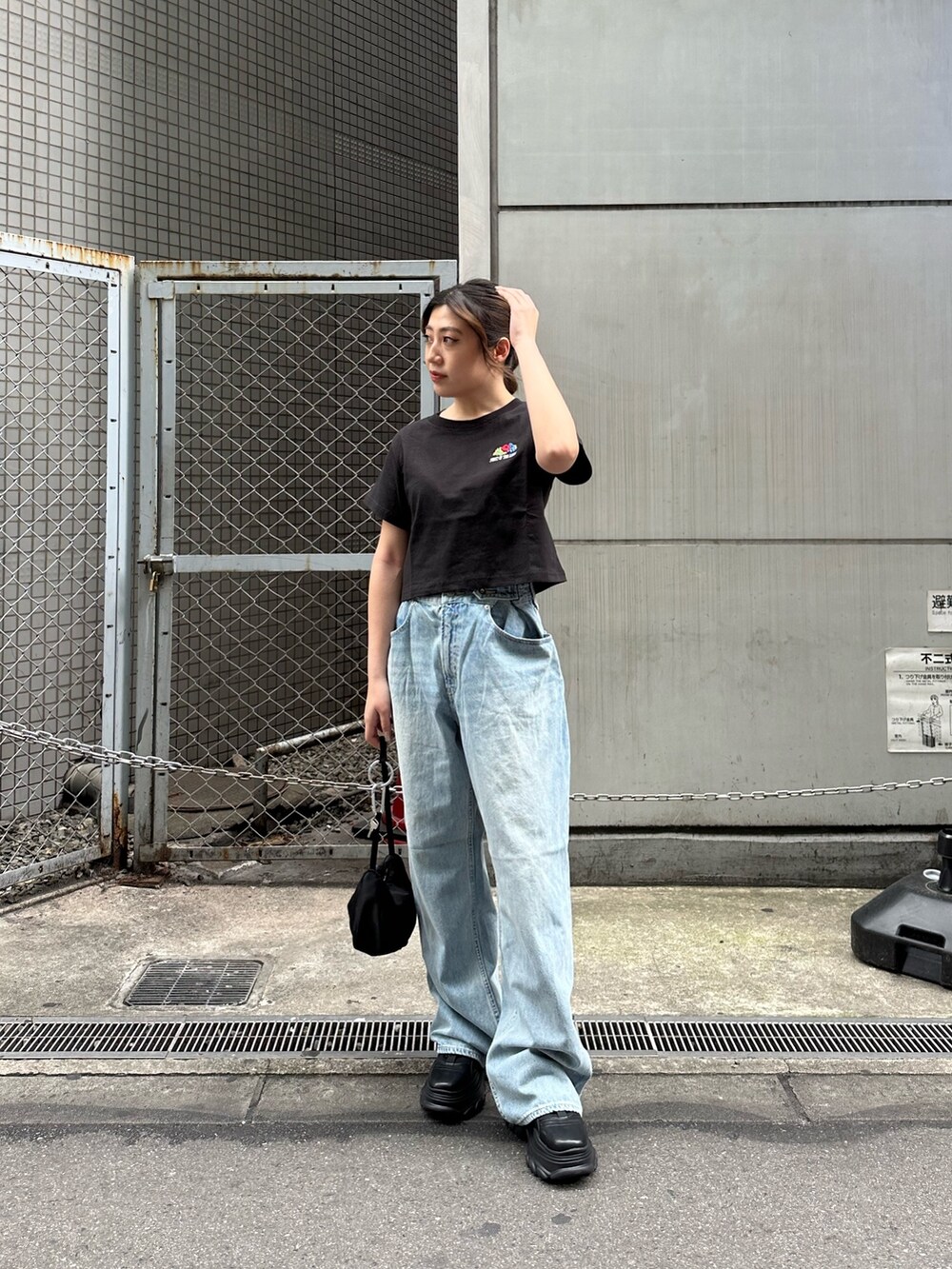 ブラック系のTシャツ/カットソー、ブラック系のスニーカー、ブルー系のデニムパンツを着用したレディースの春コーディネートの2枚目の写真