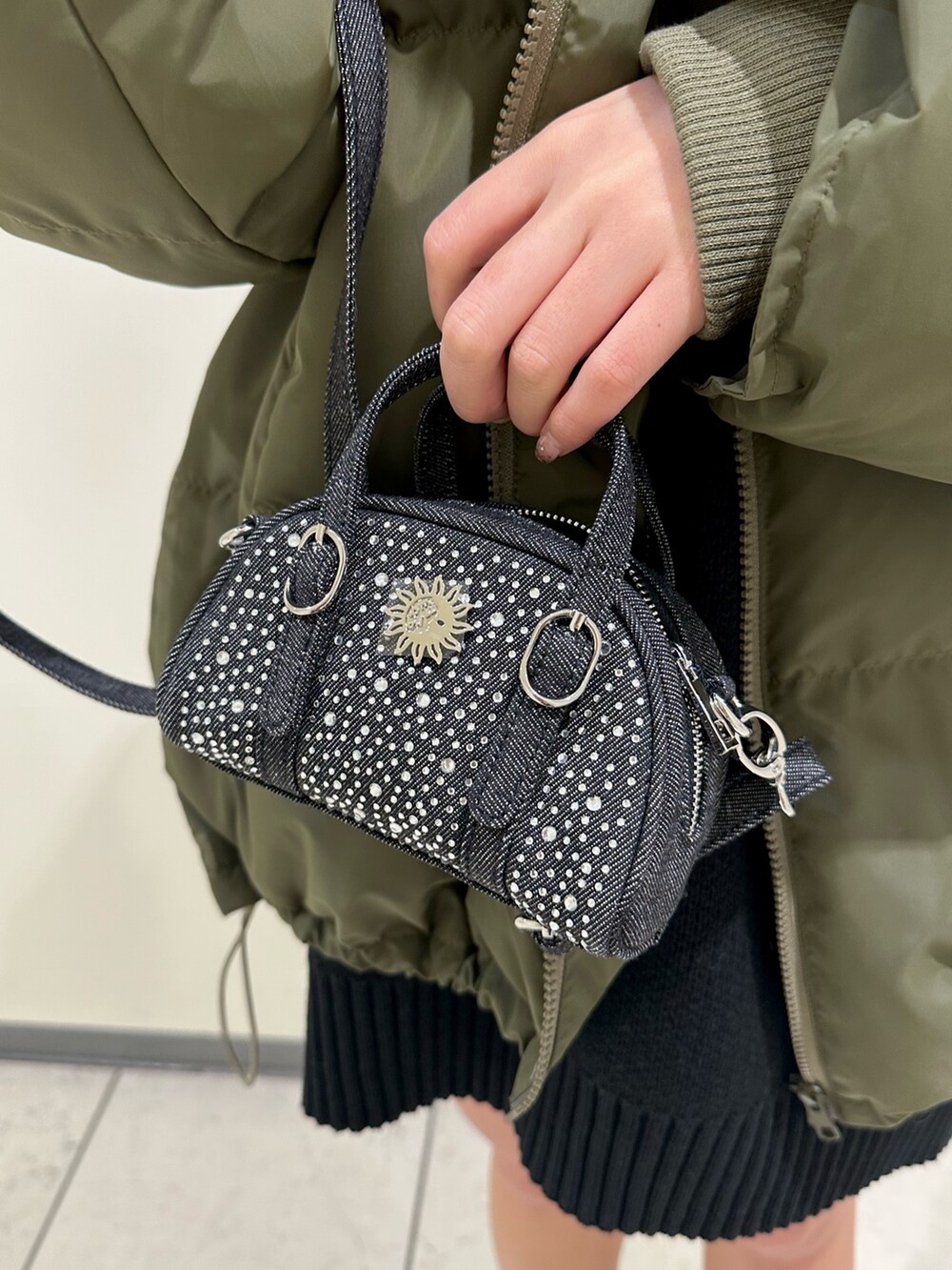 ブラック系のブーツ、ブラック系のニット/セーター、グリーン系のダウンジャケット/コートを着用したレディースの冬コーディネートの9枚目の写真