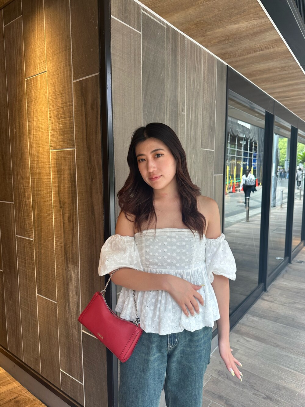 ブルー系のデニムパンツ、ホワイト系のシャツ/ブラウス、レッド系のショルダーバッグを着用したレディースの夏コーディネートの5枚目の写真