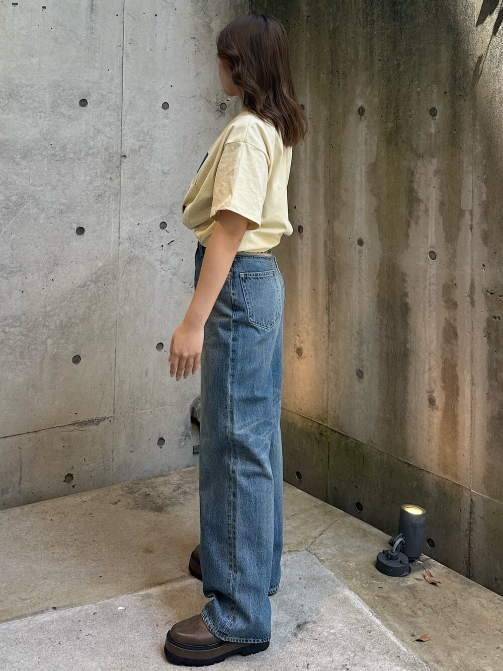 イエロー系のTシャツ/カットソー、ブルー系のデニムパンツ、ブラウン系のブーツを着用したレディースの春コーディネートの2枚目の写真