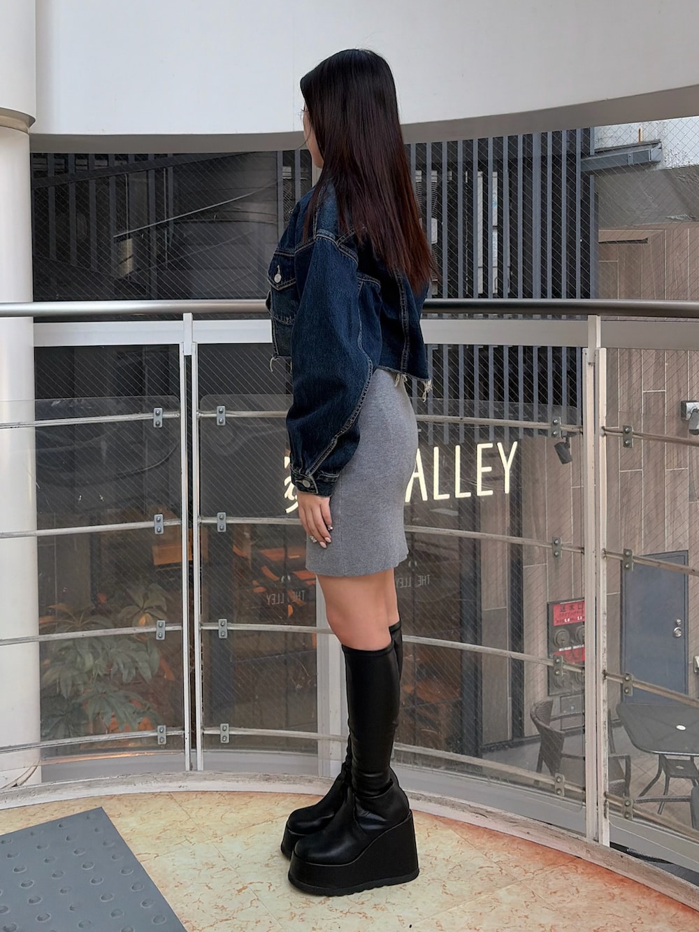 ブラック系のブーツ、ブルー系のデニムジャケット、グレー系のワンピースを着用したレディースの冬コーディネートの2枚目の写真