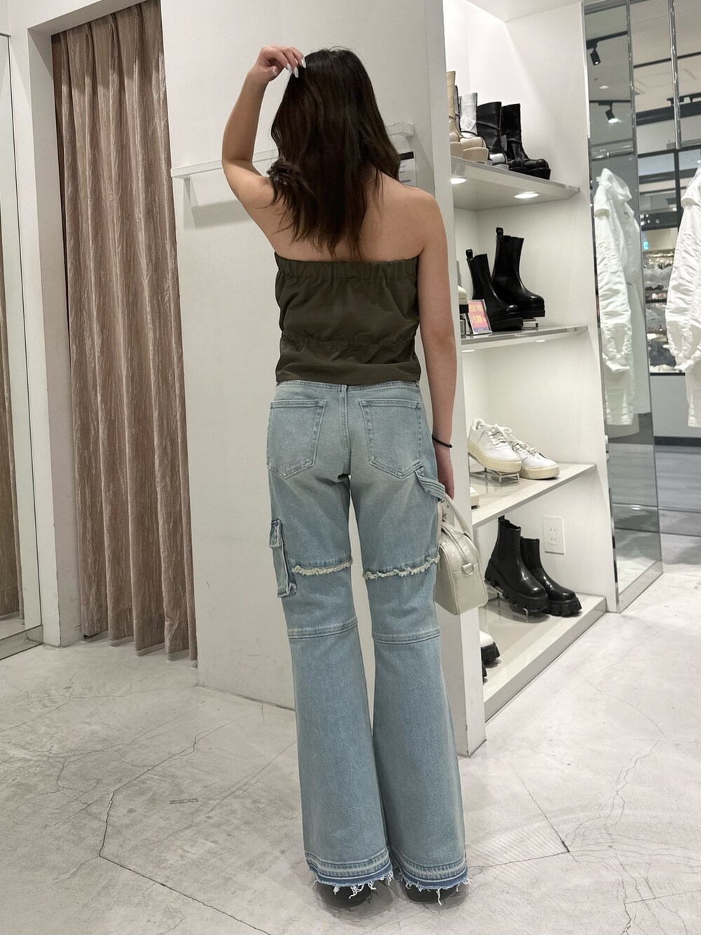 グリーン系のキャミソール、ブルー系のデニムパンツ、ホワイト系のショルダーバッグを着用したレディースの冬コーディネートの3枚目の写真