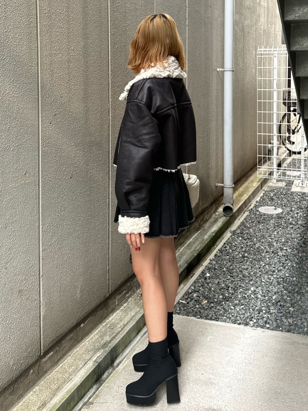 ブラック系のデニムスカート、その他のブーツ、ホワイト系のショルダーバッグを着用したレディースの秋コーディネートの2枚目の写真