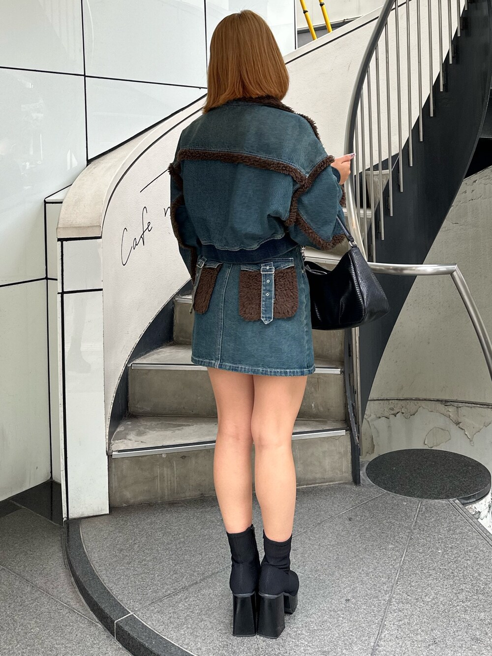 ブルー系のブルゾン、ブルー系のデニムスカート、その他のブーツを着用したレディースの秋コーディネートの3枚目の写真