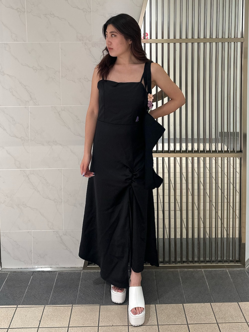 ブラック系のワンピース、ブラック系のトートバッグ、ホワイト系のサンダルを着用したレディースの夏コーディネートの2枚目の写真