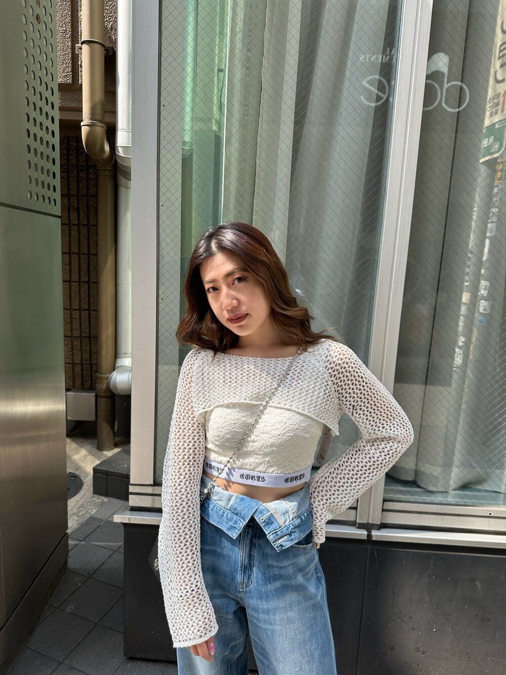 ブルー系のデニムパンツ、ホワイト系のキャミソール、ホワイト系のニット/セーターを着用したレディースの春コーディネートの3枚目の写真