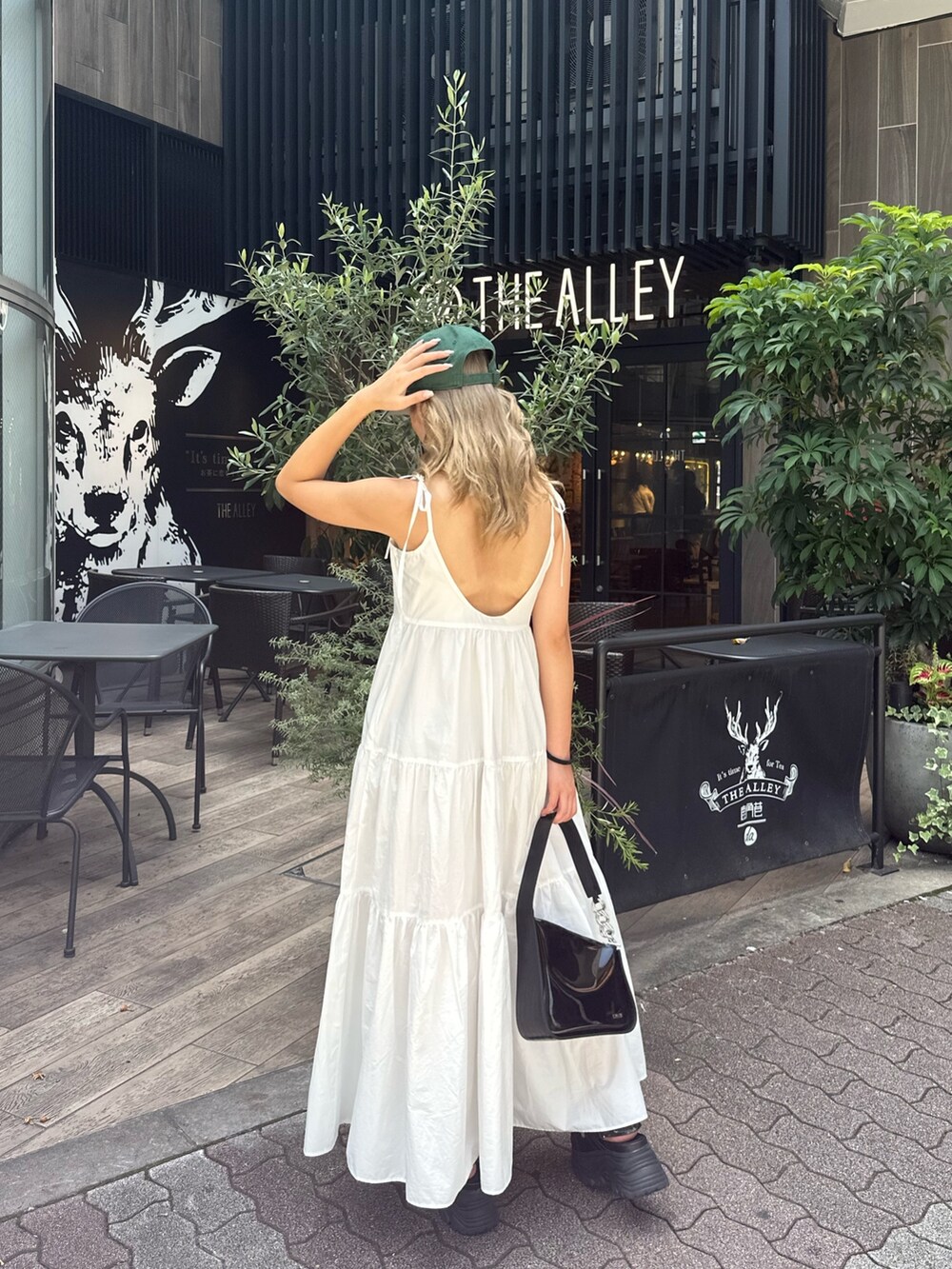 ホワイト系のワンピース、ブラック系のハンドバッグ、ブラック系のサンダルを着用したレディースの夏コーディネートの3枚目の写真