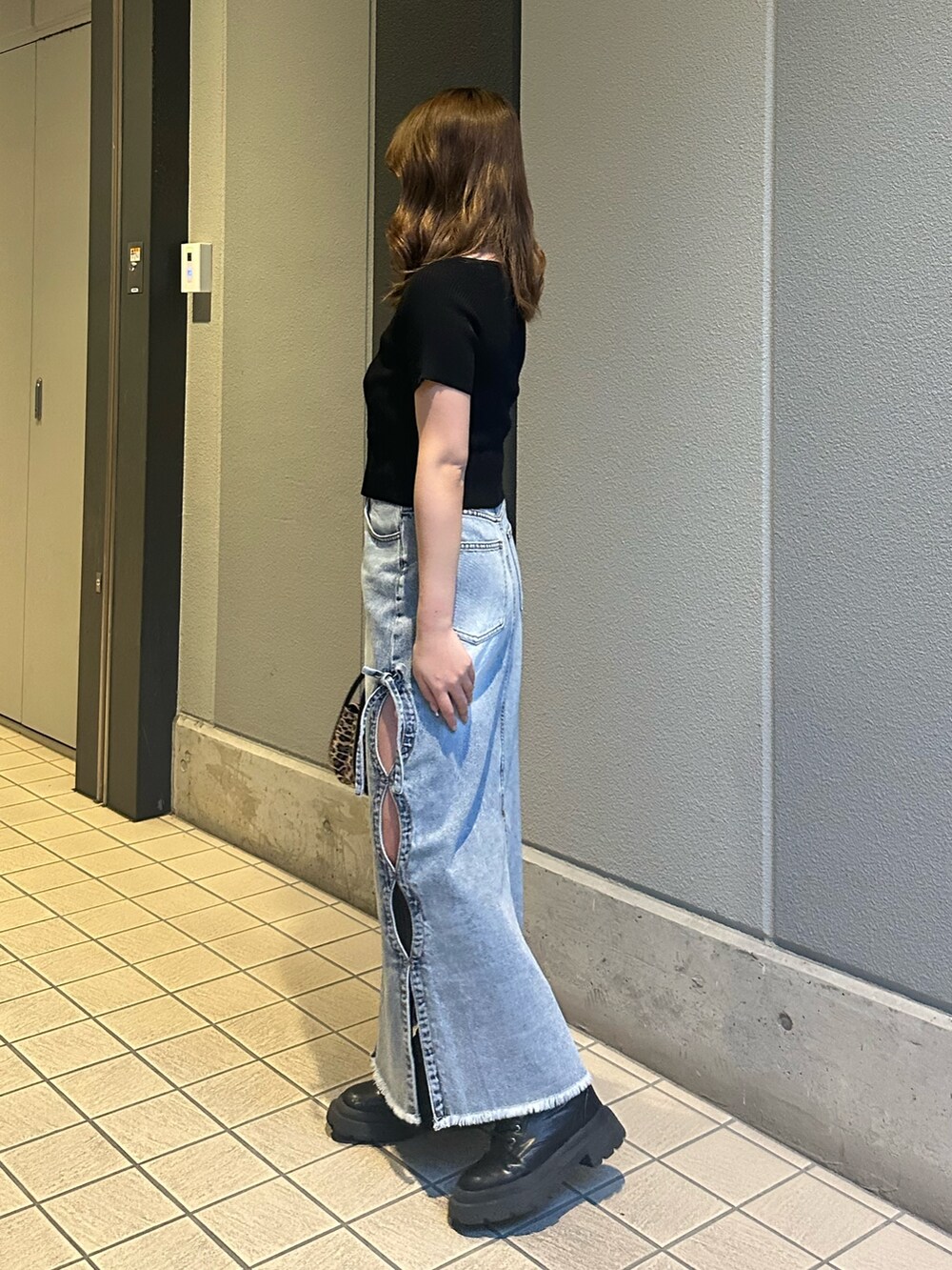 ブルー系のデニムスカート、その他のハンドバッグ、ブラック系のブーツを着用したレディースの春コーディネートの2枚目の写真