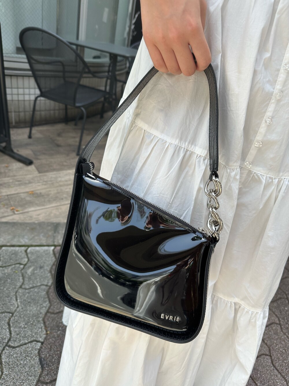 ホワイト系のワンピース、ブラック系のハンドバッグ、ブラック系のサンダルを着用したレディースの夏コーディネートの7枚目の写真