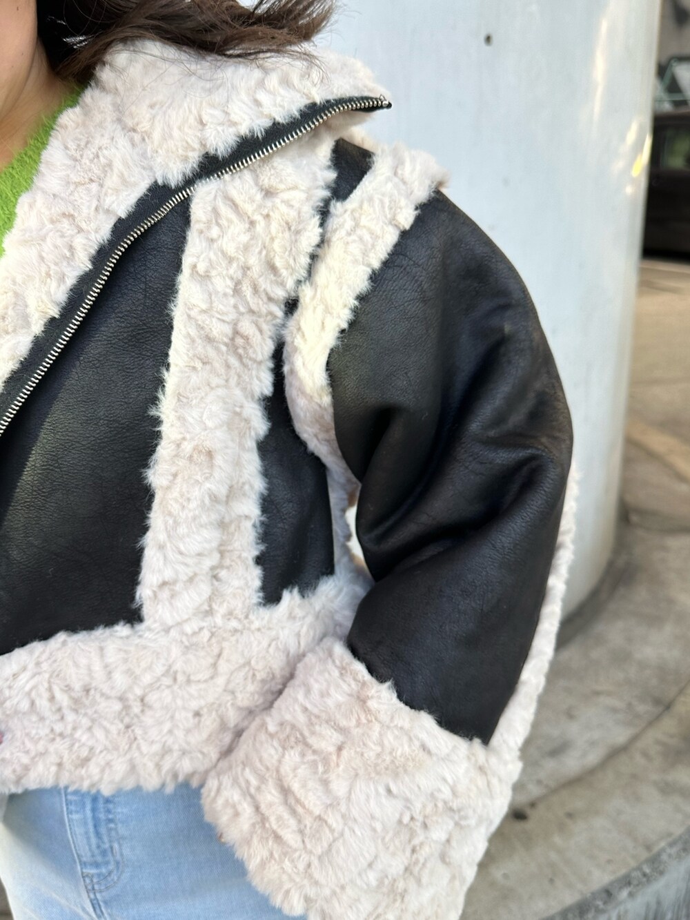 ブルー系のデニムスカート、グリーン系のニット/セーター、ブラック系のムートンコートを着用したレディースの冬コーディネートの4枚目の写真