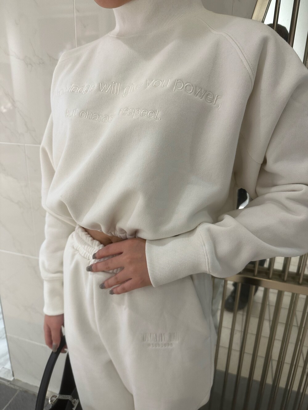 ホワイト系のスウェットパンツ、ホワイト系のスウェット、ブラック系のブーツを着用したレディースの秋コーディネートの5枚目の写真