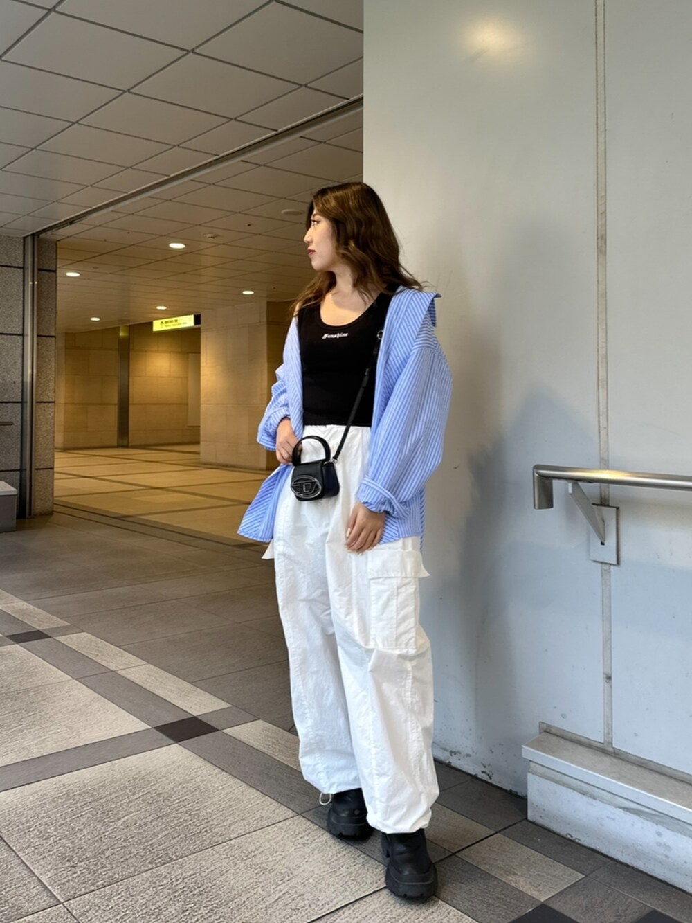 ブラック系のタンクトップ、ブルー系のシャツ/ブラウス、ホワイト系のカーゴパンツを着用したレディースの春コーディネートの2枚目の写真