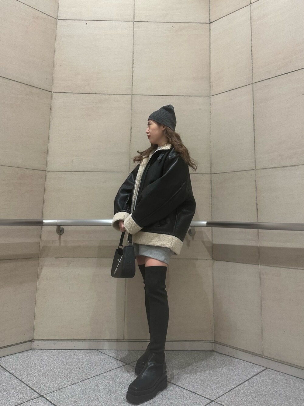 グレー系のスウェット、ブラック系のブルゾン、ブラック系のハンドバッグを着用したレディースの冬コーディネートの2枚目の写真