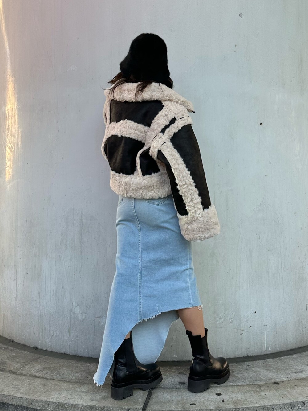 ブルー系のデニムスカート、グリーン系のニット/セーター、ブラック系のムートンコートを着用したレディースの冬コーディネートの2枚目の写真