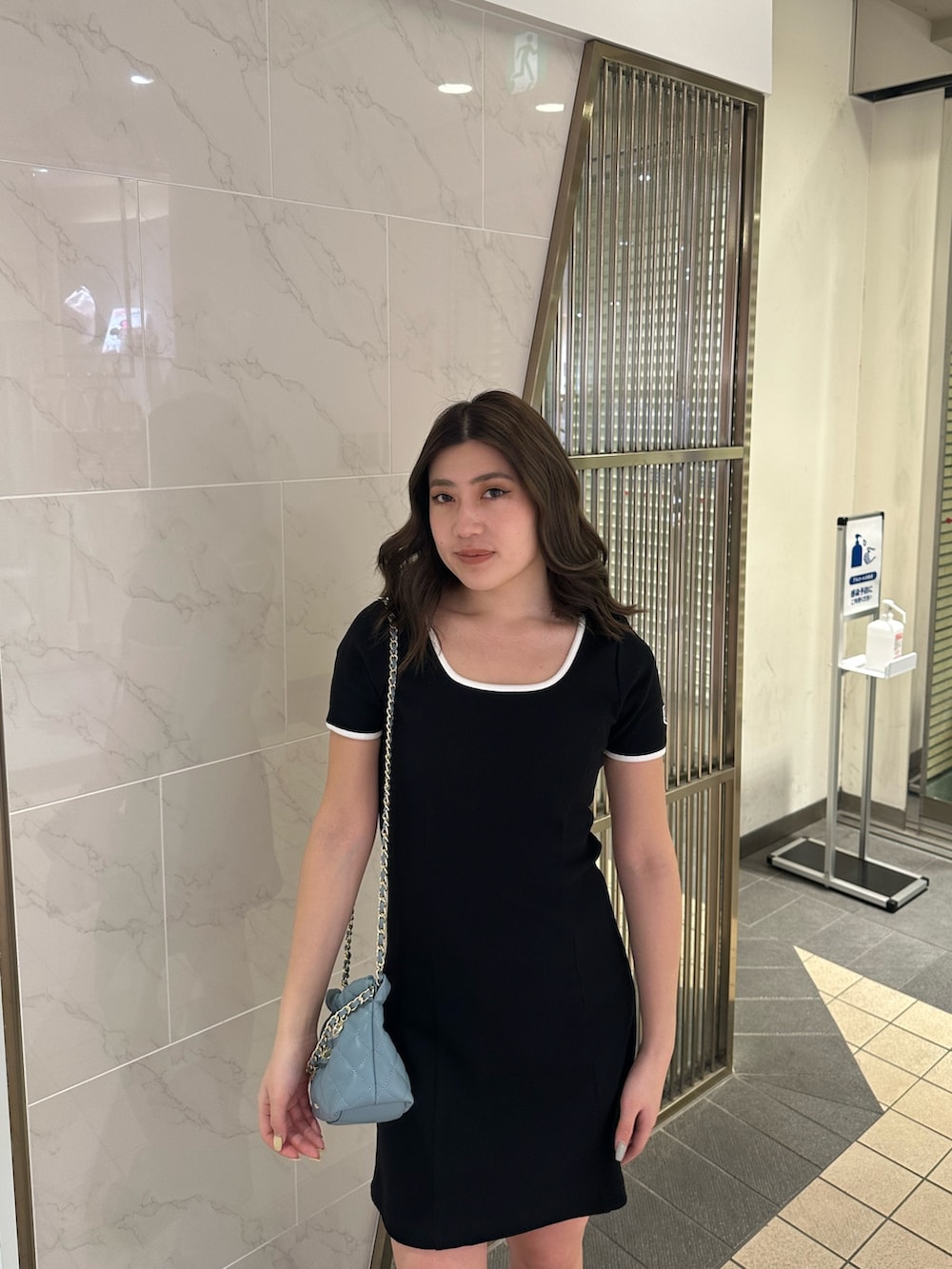 ブルー系のショルダーバッグ、ブラウン系のブーツ、ブラック系のワンピースを着用したレディースの春コーディネートの4枚目の写真