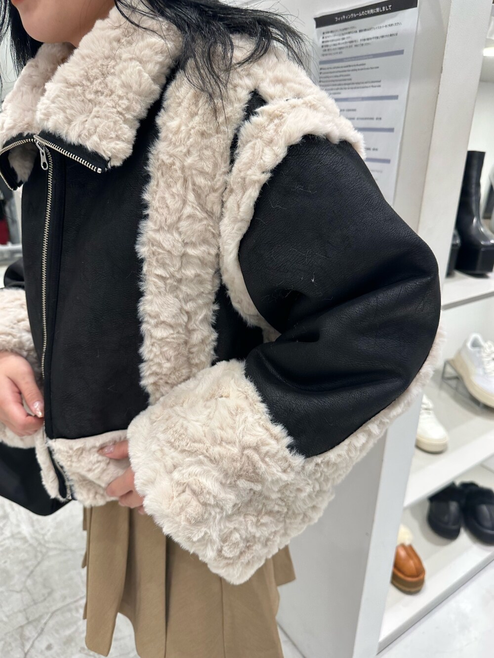 ブラック系のムートンコート、ベージュ系のスカート、ブラック系のハンドバッグを着用したレディースの冬コーディネートの6枚目の写真