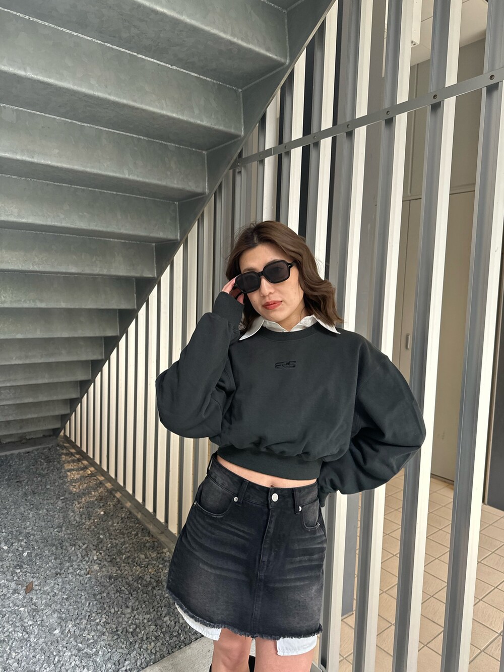 ブラック系のデニムスカート、ブラウン系のブーツ、ブラック系のスウェットを着用したレディースの冬コーディネートの4枚目の写真