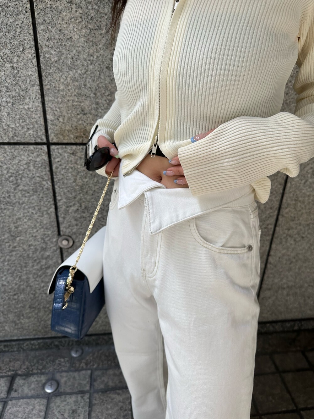 ホワイト系のニット/セーター、ホワイト系のデニムパンツ、ブルー系のショルダーバッグを着用したレディースの春コーディネートの6枚目の写真