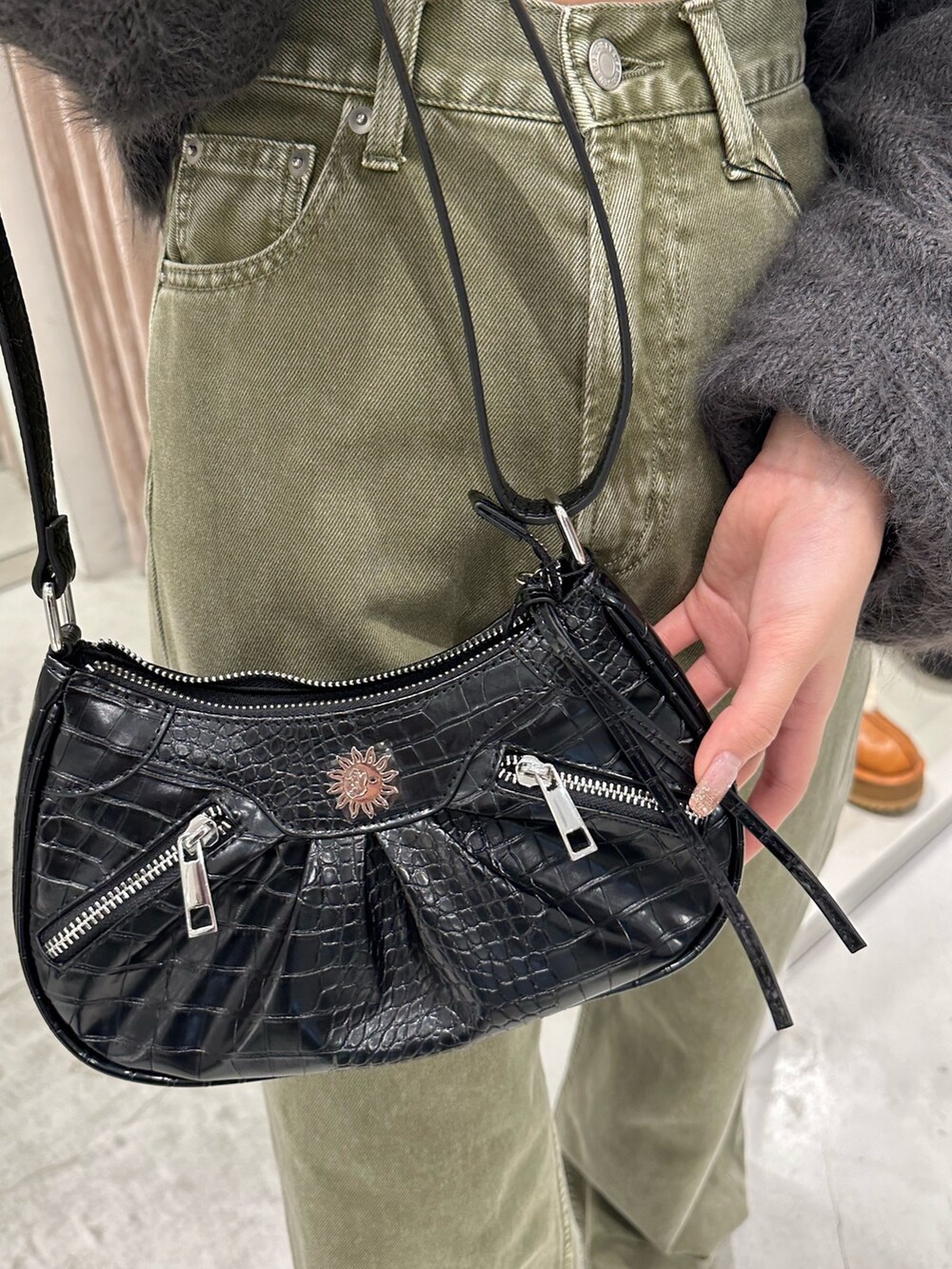 グリーン系のデニムパンツ、グレー系のニット/セーター、ブラック系のショルダーバッグを着用したレディースの冬コーディネートの8枚目の写真
