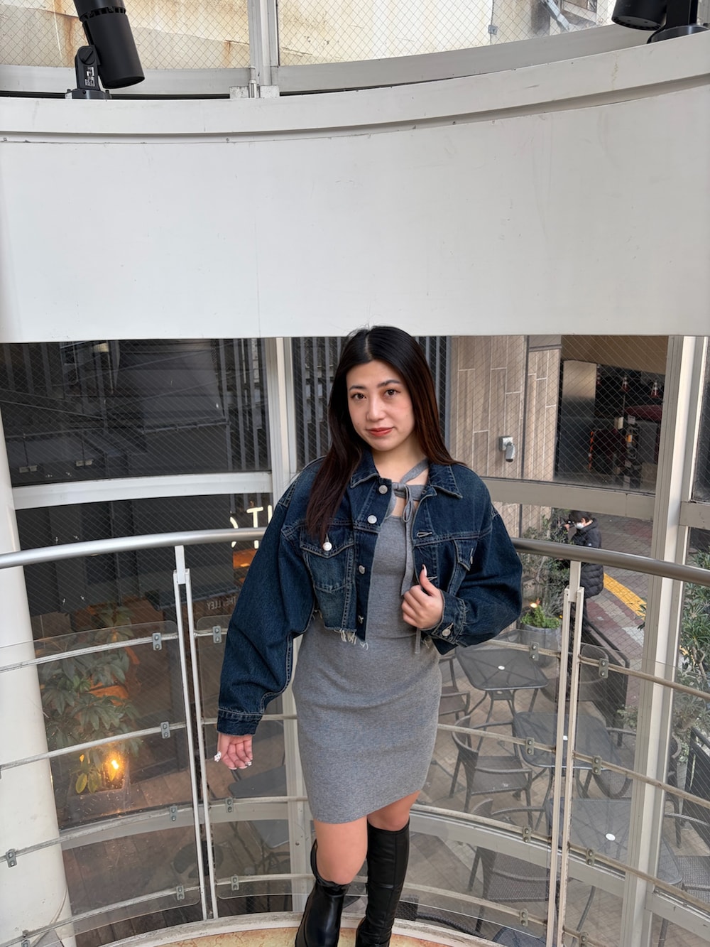 ブラック系のブーツ、ブルー系のデニムジャケット、グレー系のワンピースを着用したレディースの冬コーディネートの5枚目の写真