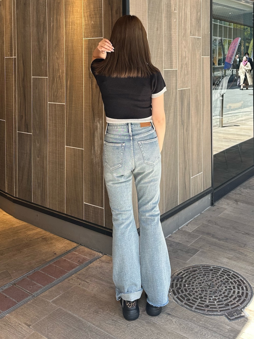 ブラック系のニット/セーター、ブルー系のデニムパンツ、その他のサンダルを着用したレディースの春コーディネートの3枚目の写真