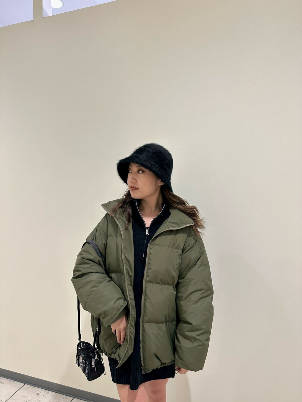 ブラック系のブーツ、ブラック系のニット/セーター、グリーン系のダウンジャケット/コートを着用したレディースの冬コーディネートの4枚目の写真