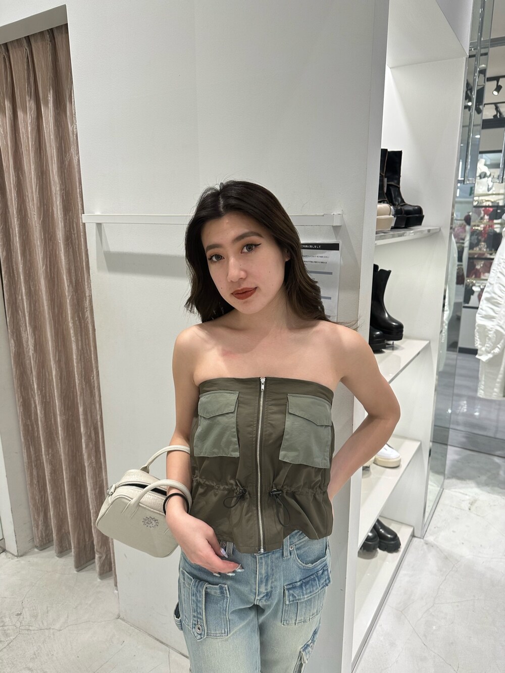 グリーン系のキャミソール、ブルー系のデニムパンツ、ホワイト系のショルダーバッグを着用したレディースの冬コーディネートの4枚目の写真