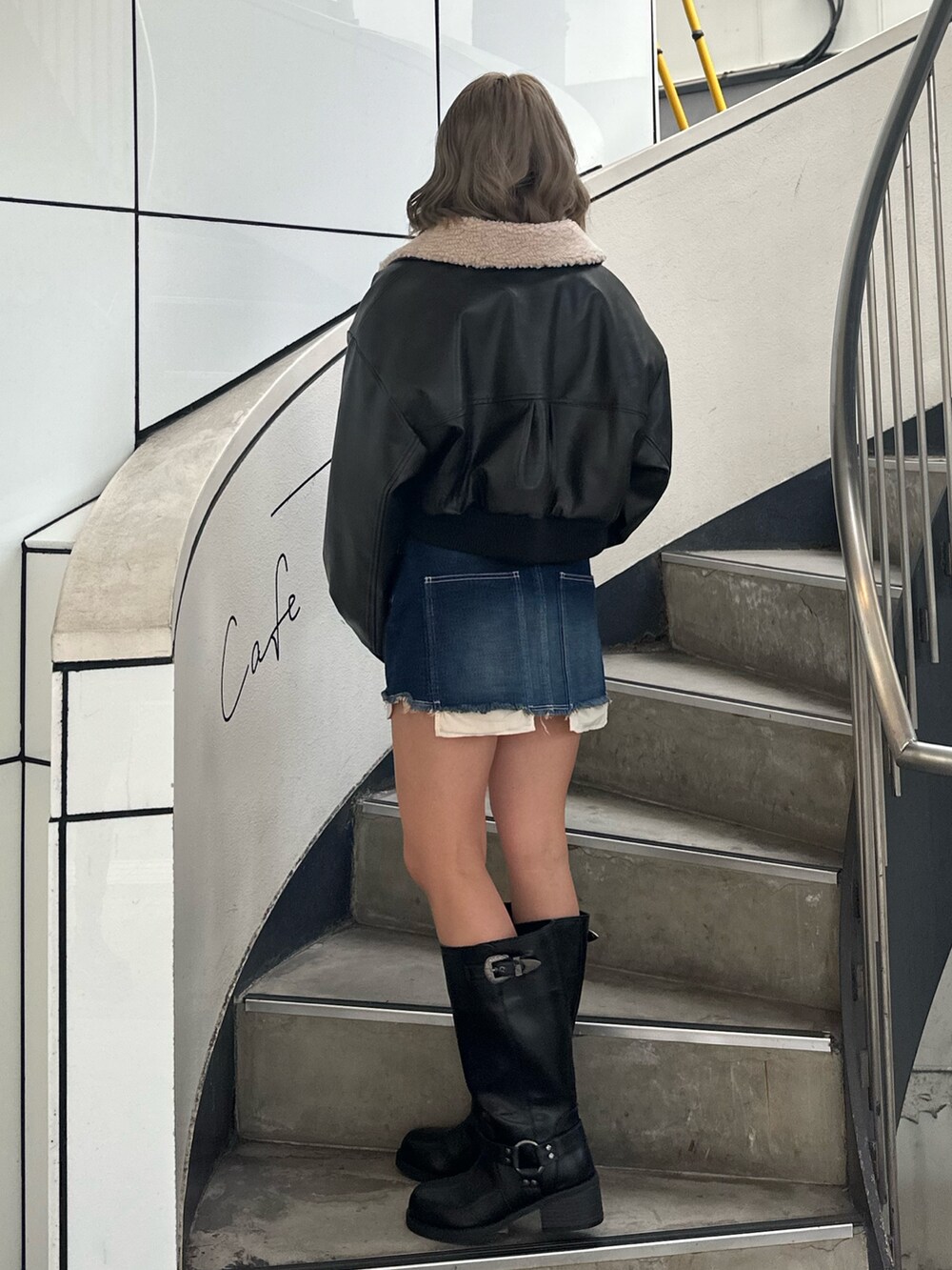 ブルー系のデニムスカート、ブラック系のブーツ、ブラック系のブルゾンを着用したレディースの冬コーディネートの2枚目の写真