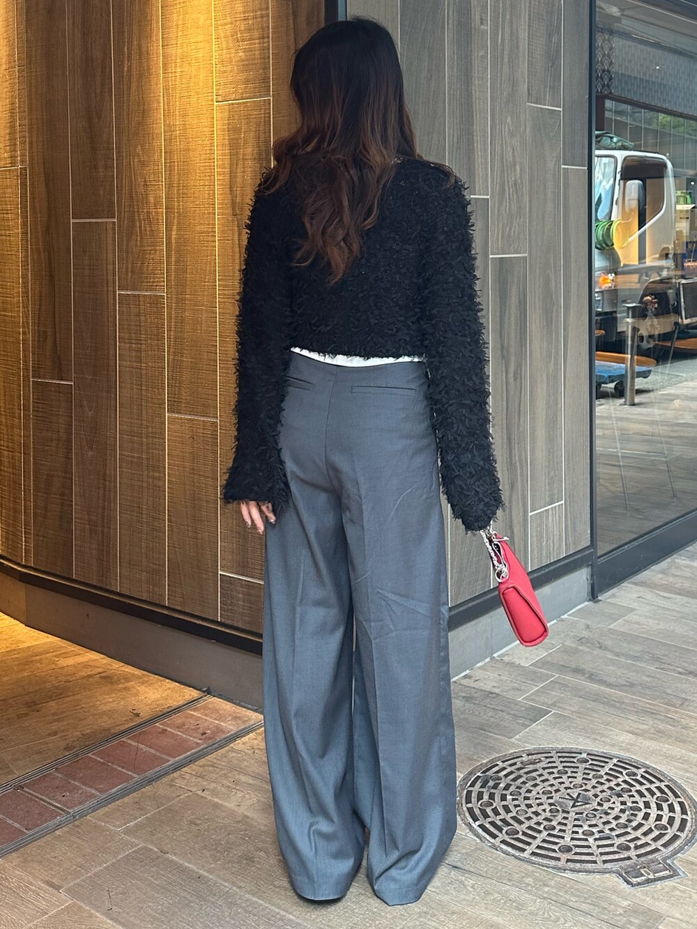 ブラック系のニット/セーター、グレー系のその他パンツ、レッド系のショルダーバッグを着用したレディースの秋コーディネートの3枚目の写真