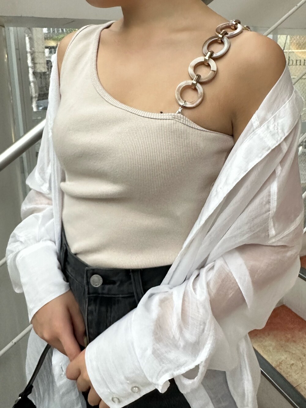 ブラック系のサンダル、ブラック系のハンドバッグ、ブラック系のデニムパンツを着用したレディースの夏コーディネートの5枚目の写真