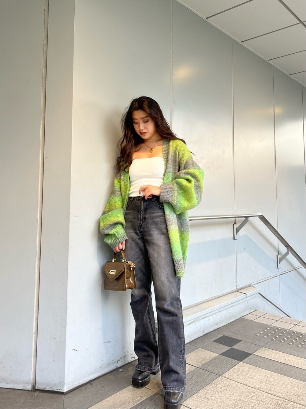 グリーン系のカーディガン/ボレロ、ホワイト系のチューブトップ、ブラック系のデニムパンツを着用したレディースの秋コーディネートの2枚目の写真