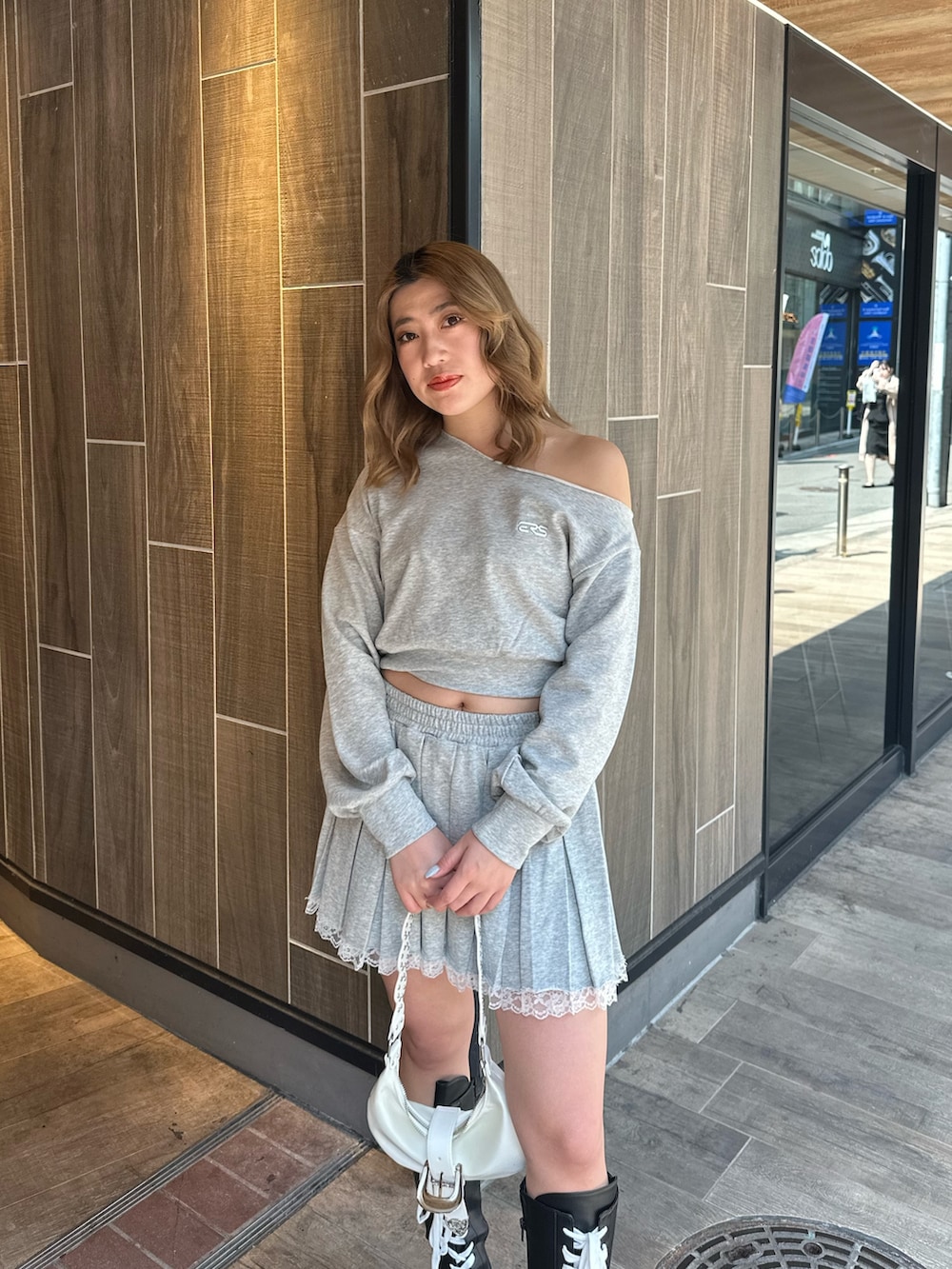 ホワイト系のショルダーバッグ、ブラック系のブーツ、グレー系のスウェットを着用したレディースの春コーディネートの4枚目の写真