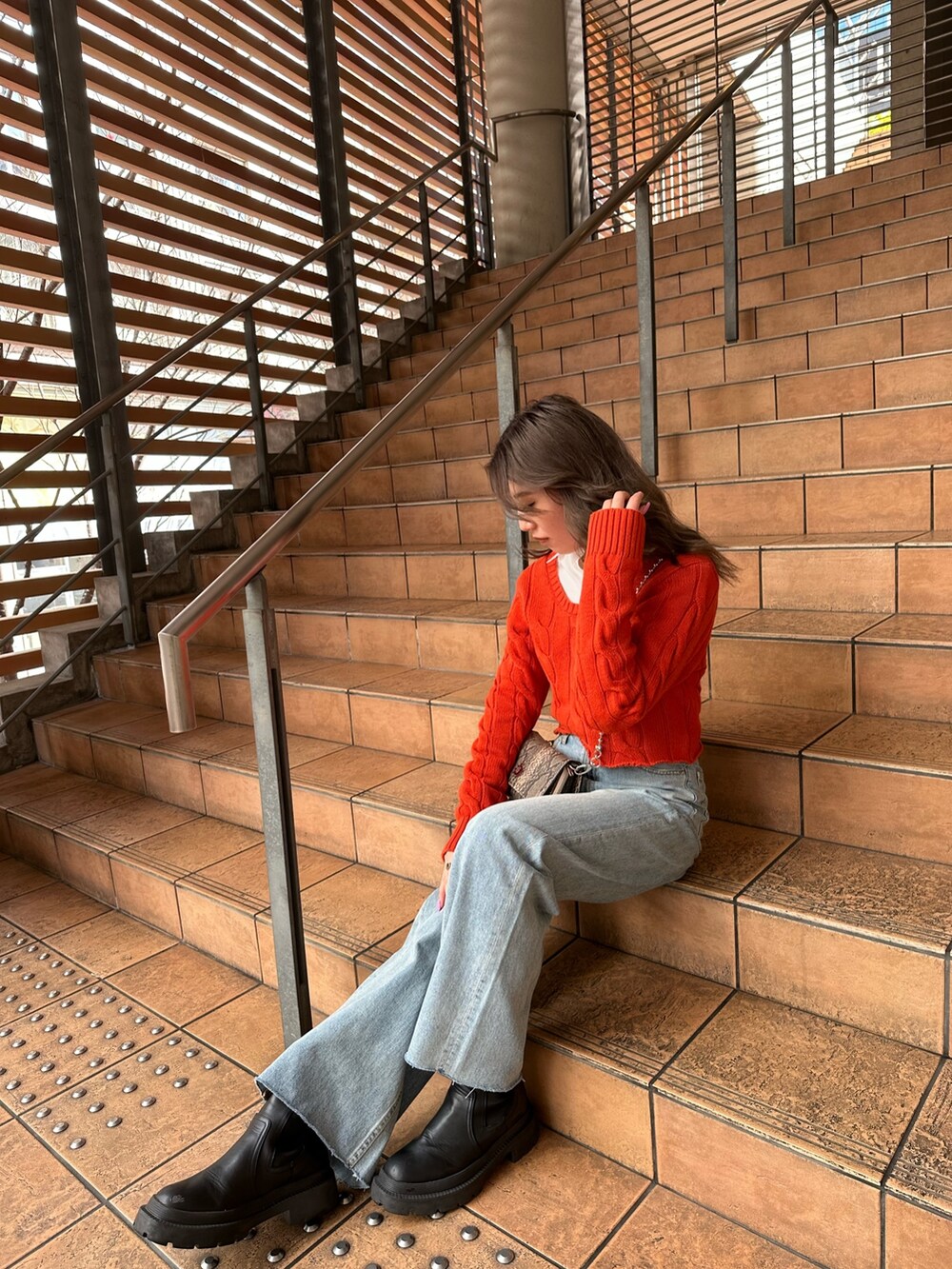 オレンジ系のカーディガン/ボレロ、ホワイト系のシャツ/ブラウス、ブルー系のデニムパンツを着用したレディースの冬コーディネートの3枚目の写真