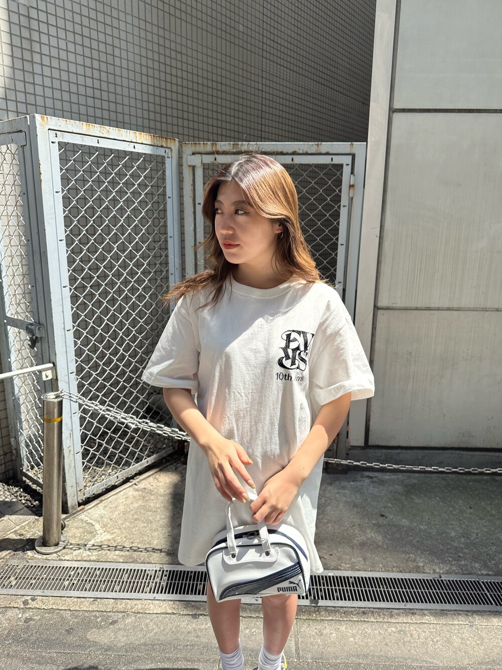 ホワイト系のTシャツ/カットソー、ホワイト系のサンダル、ホワイト系のハンドバッグを着用したレディースの春コーディネートの3枚目の写真