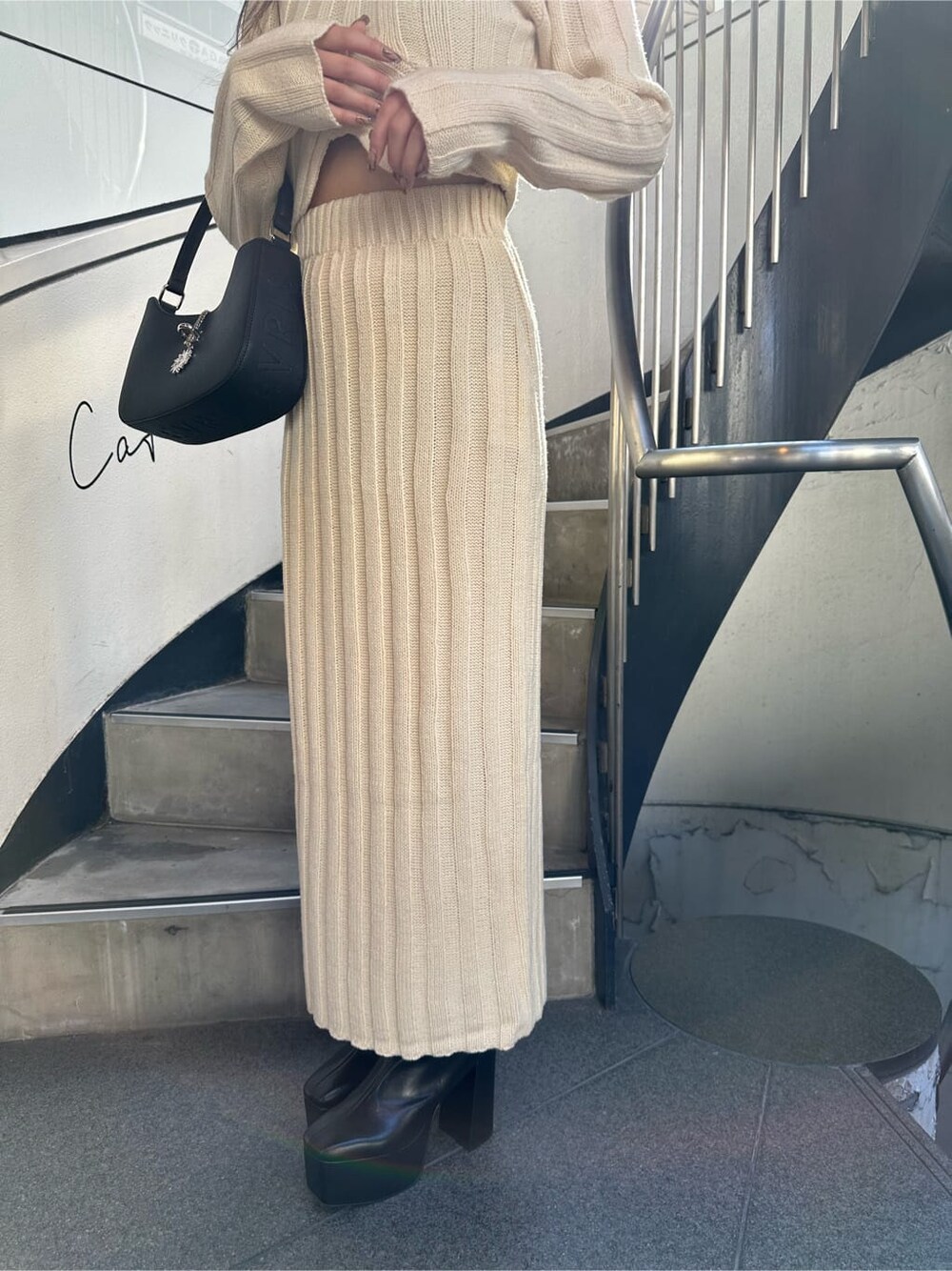 ホワイト系のスカート、ホワイト系のニット/セーター、ブラック系のハンドバッグを着用したレディースの秋コーディネートの6枚目の写真